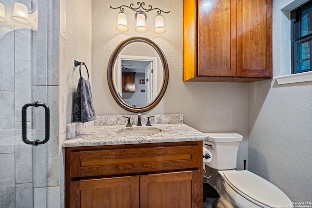 bathroom featuring a shower with shower door, toilet, vanity, and a textured wall
