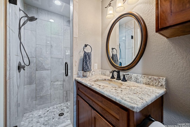 full bathroom featuring a textured wall, vanity, and a stall shower