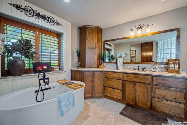 bathroom with tile patterned flooring, a bathtub, a textured ceiling, and vanity