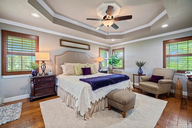 bedroom featuring ornamental molding, baseboards, a raised ceiling, and hardwood / wood-style floors