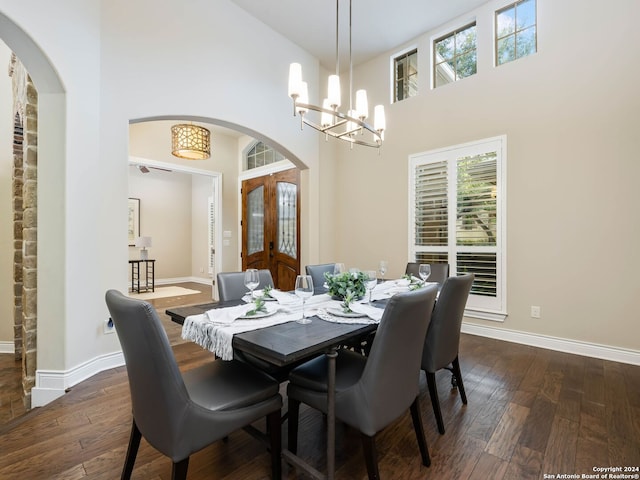 dining space featuring a towering ceiling, an inviting chandelier, and dark hardwood / wood-style flooring