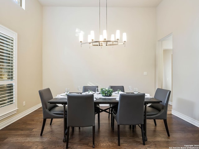 dining area with dark hardwood / wood-style flooring, a high ceiling, and a chandelier