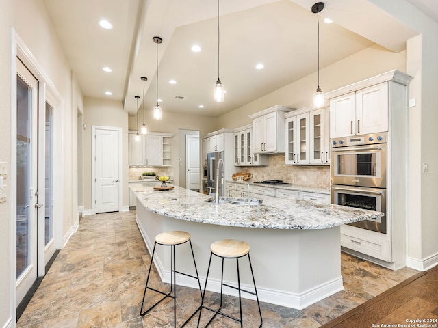 kitchen featuring appliances with stainless steel finishes, a breakfast bar, decorative backsplash, and white cabinetry