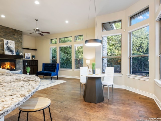 living room with plenty of natural light, ceiling fan, a large fireplace, and dark hardwood / wood-style flooring