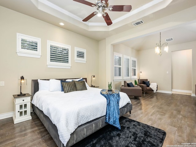 bedroom with ceiling fan with notable chandelier, dark hardwood / wood-style floors, and a raised ceiling