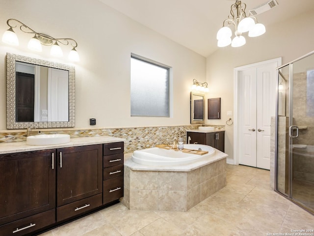 bathroom with an inviting chandelier, independent shower and bath, tile patterned floors, and vanity