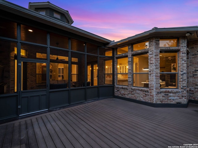 deck at dusk featuring a sunroom