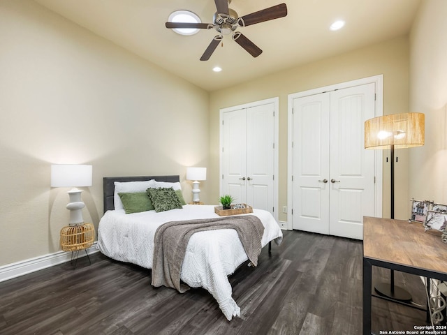 bedroom with ceiling fan, dark hardwood / wood-style floors, and multiple closets