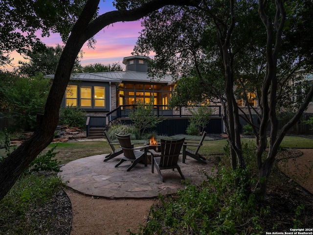 back house at dusk with an outdoor fire pit and a patio