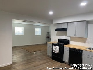 kitchen with gray cabinetry, black appliances, and wood-type flooring