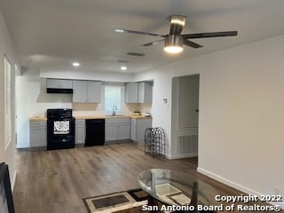 kitchen with hardwood / wood-style floors, gray cabinetry, stove, black dishwasher, and ceiling fan