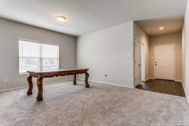 unfurnished office featuring dark carpet and baseboards