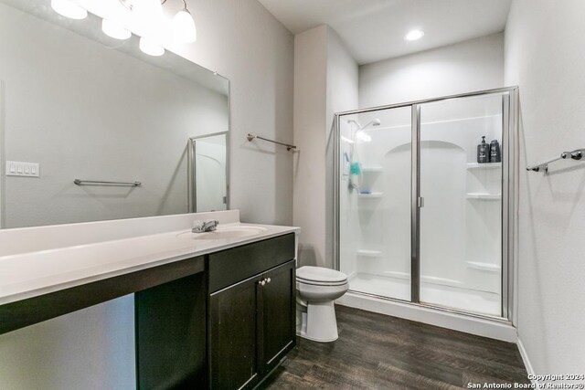 bathroom featuring a shower with door, vanity, toilet, and wood-type flooring