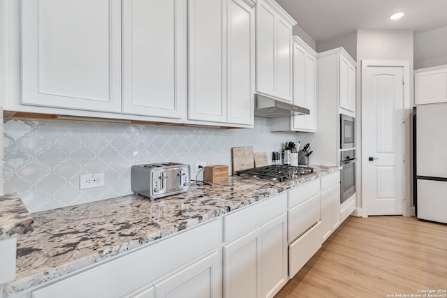 kitchen featuring stainless steel appliances, light hardwood / wood-style floors, decorative backsplash, white cabinetry, and light stone counters