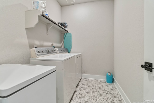 clothes washing area with washing machine and dryer and light tile patterned floors