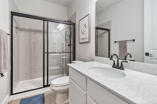 bathroom with hardwood / wood-style floors, toilet, walk in shower, and vanity