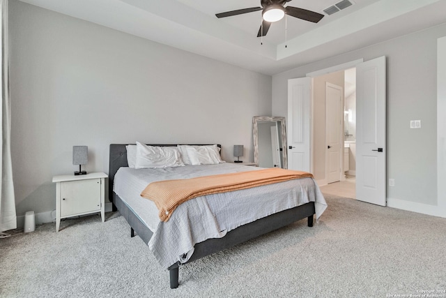 carpeted bedroom featuring a tray ceiling, ceiling fan, and connected bathroom