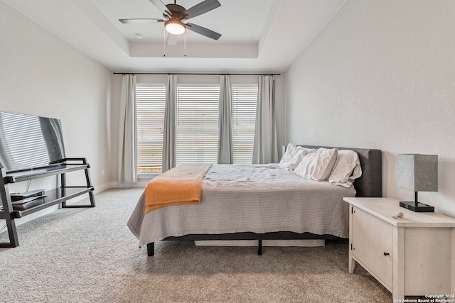 carpeted bedroom featuring ceiling fan and a raised ceiling