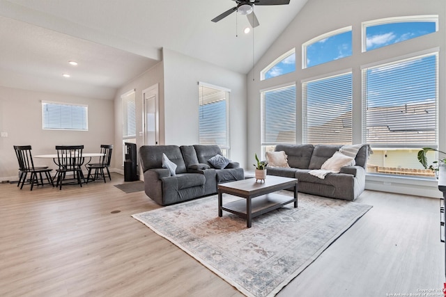 living room with ceiling fan, high vaulted ceiling, and light hardwood / wood-style floors