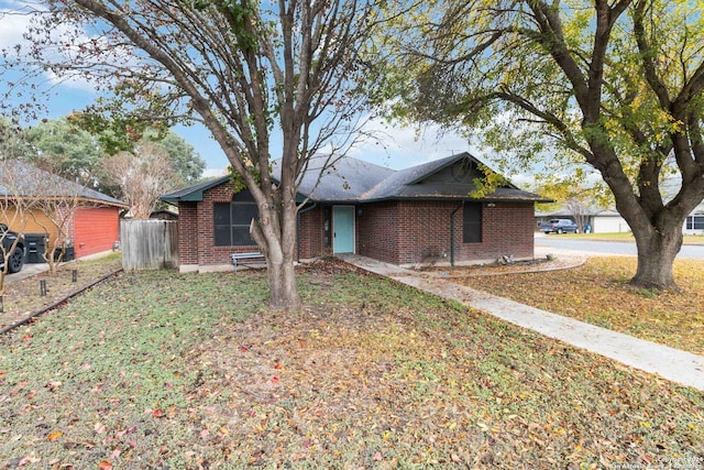 ranch-style home featuring brick siding, a front yard, and fence