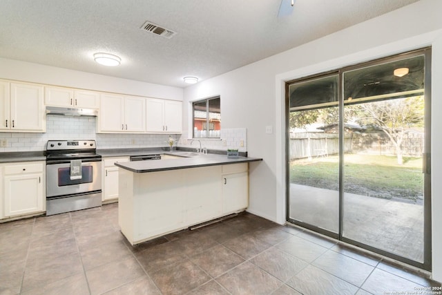 kitchen with dark countertops, visible vents, stainless steel range with electric cooktop, a peninsula, and under cabinet range hood