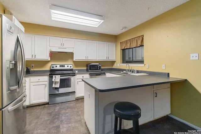 kitchen featuring a kitchen breakfast bar, kitchen peninsula, sink, appliances with stainless steel finishes, and white cabinetry