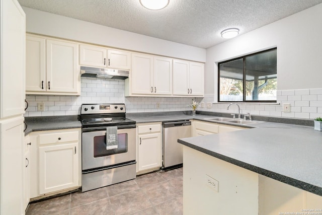 kitchen featuring dark countertops, appliances with stainless steel finishes, a sink, under cabinet range hood, and backsplash