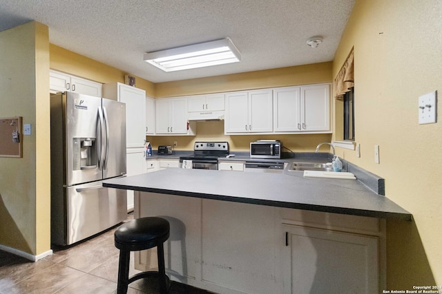 kitchen featuring white cabinetry, sink, stainless steel appliances, a kitchen breakfast bar, and kitchen peninsula