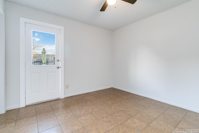 empty room with a ceiling fan, baseboards, and light tile patterned floors