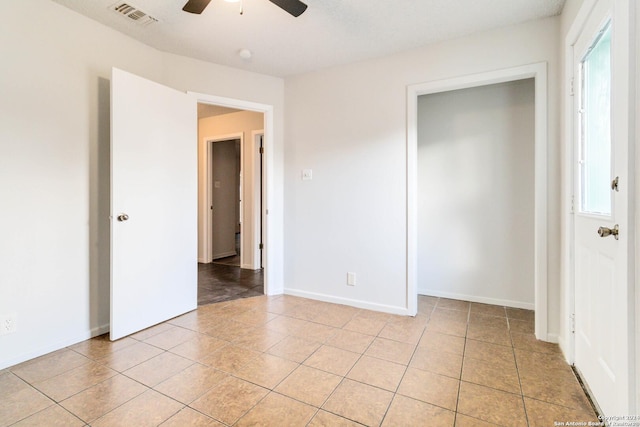 unfurnished bedroom with light tile patterned floors, baseboards, visible vents, and a ceiling fan