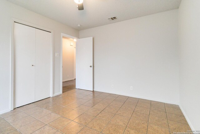 unfurnished bedroom with ceiling fan, visible vents, a closet, and light tile patterned flooring