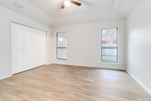 unfurnished bedroom featuring a ceiling fan, baseboards, visible vents, light wood-style floors, and a closet