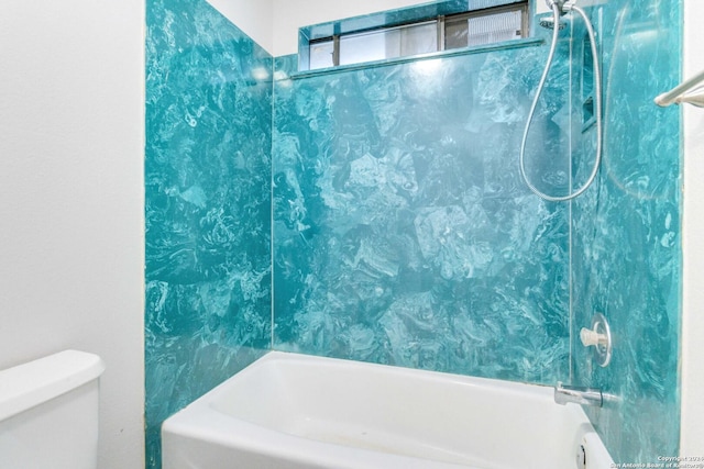 bathroom featuring tiled shower / bath combo and toilet