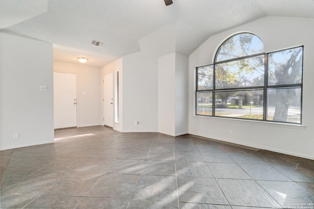 unfurnished room with vaulted ceiling, a wealth of natural light, visible vents, and a ceiling fan