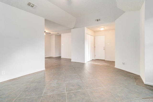 tiled spare room featuring ceiling fan, visible vents, and baseboards