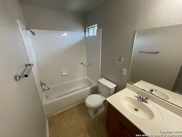 full bathroom with tiled shower / bath combo, toilet, tile patterned floors, and vanity