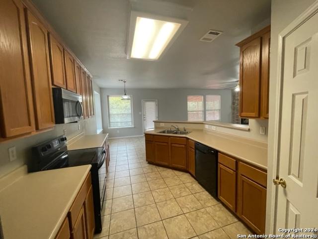 kitchen featuring black dishwasher, range, a wealth of natural light, and hanging light fixtures