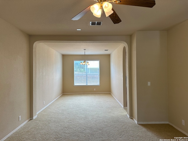 carpeted empty room with ceiling fan with notable chandelier