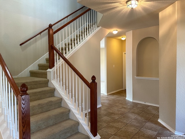 staircase featuring a textured ceiling and tile patterned floors