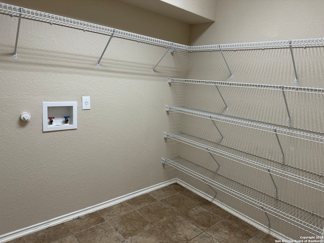 washroom with dark tile patterned flooring and hookup for a washing machine