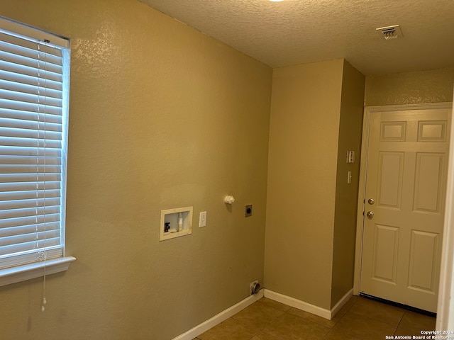 washroom featuring electric dryer hookup, a textured ceiling, tile patterned flooring, and washer hookup