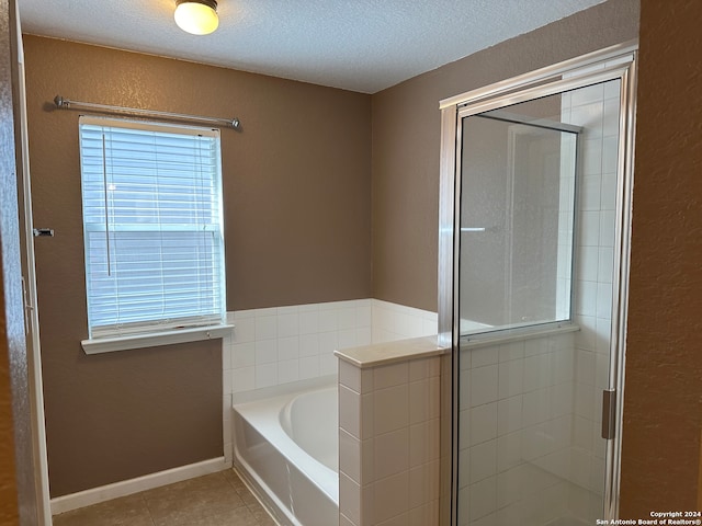 bathroom with shower with separate bathtub, a textured ceiling, and tile patterned flooring