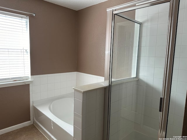 bathroom with a textured ceiling, separate shower and tub, and tile patterned floors