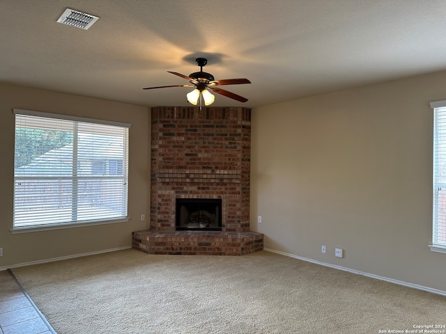 unfurnished living room with light carpet, plenty of natural light, and a brick fireplace