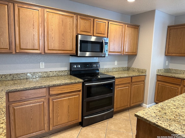 kitchen featuring light tile patterned floors, black electric range, and light stone counters