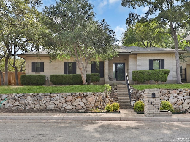 ranch-style home featuring brick siding and fence