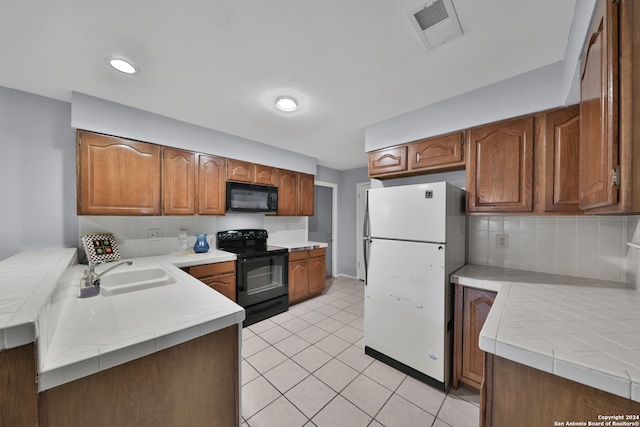 kitchen with backsplash, sink, tile counters, light tile patterned floors, and black appliances