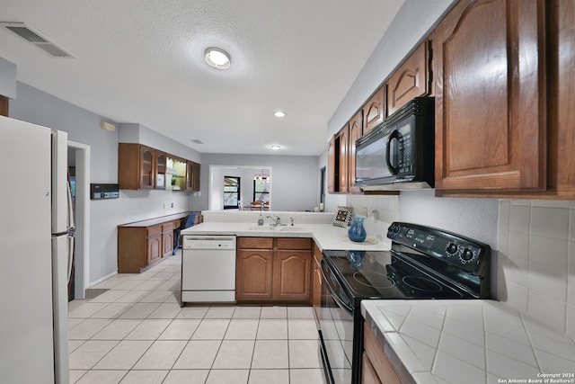 kitchen featuring light tile patterned flooring, kitchen peninsula, tasteful backsplash, and black appliances