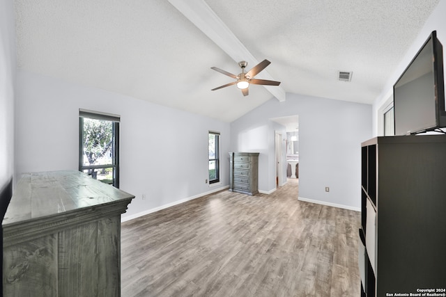 unfurnished bedroom featuring connected bathroom, a textured ceiling, hardwood / wood-style floors, and lofted ceiling with beams