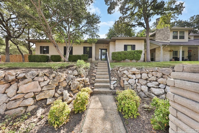 view of front of home featuring brick siding, a chimney, and fence